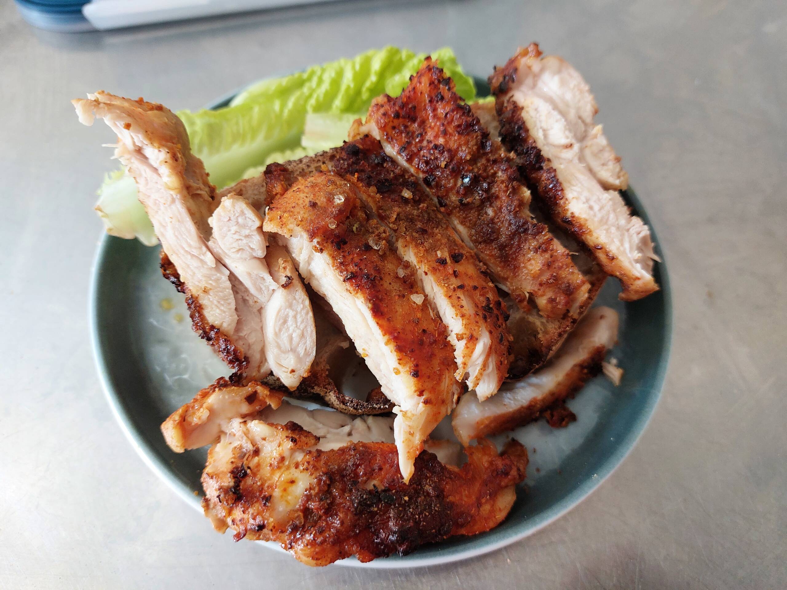 seared and seasoned chicken breast, resting on a bed of crisp, fresh lettuce