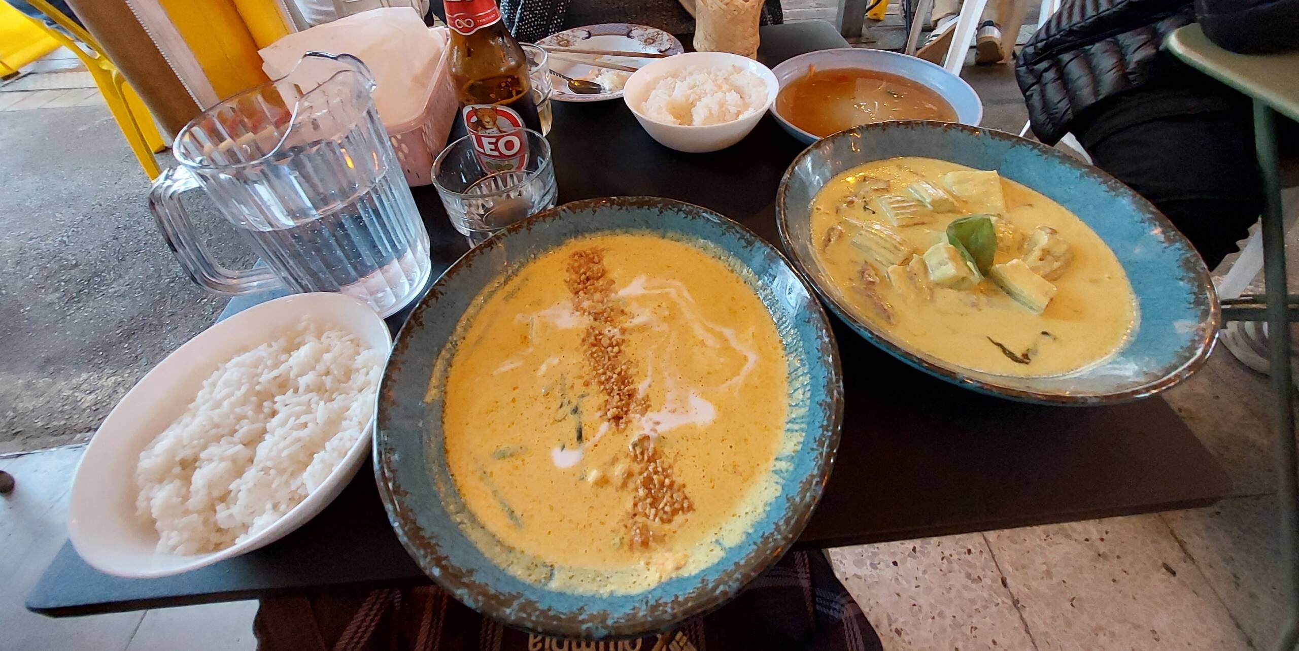 A Flavorful Thai Feast: Creamy Curries and Steamed Rice in a Street-Side Setting