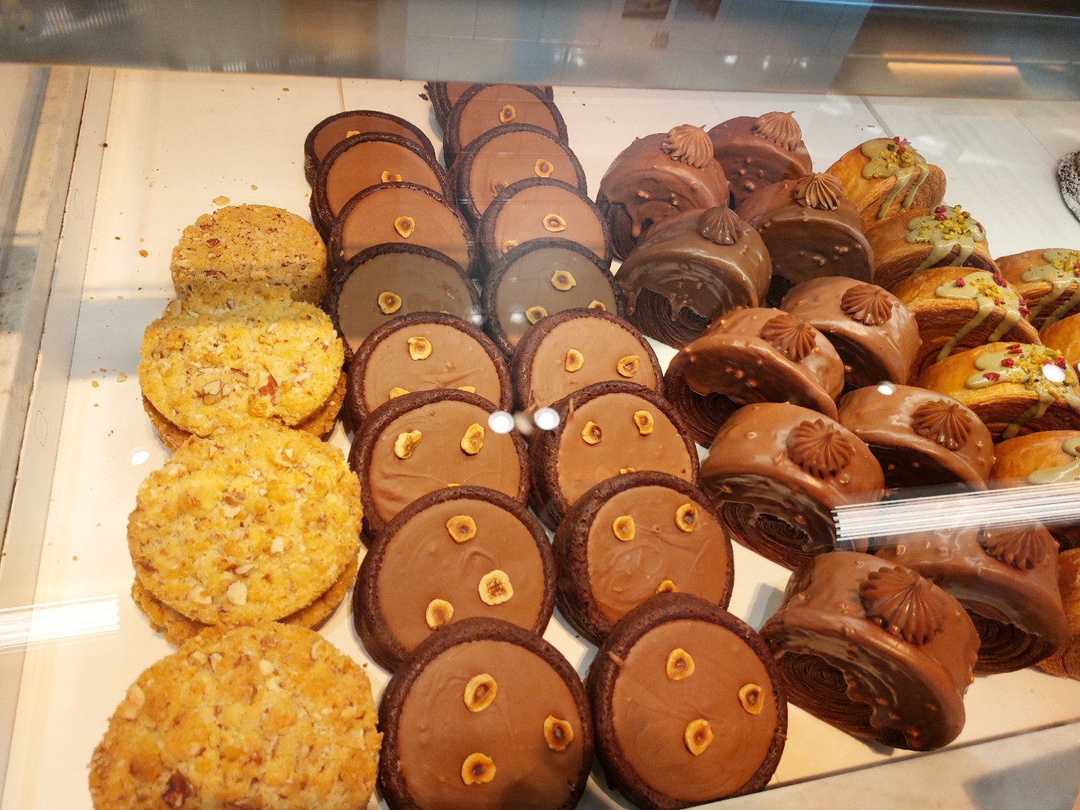 Golden nut pastries, chocolate hazelnut rounds and chocolate-covered layered pastries in a bakery display